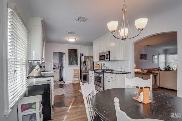 kitchen with arched walkways, stainless steel appliances, visible vents, and white cabinetry