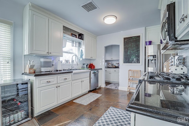 kitchen featuring visible vents, wine cooler, stainless steel appliances, stone tile flooring, and a sink