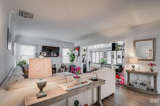 living area featuring plenty of natural light, visible vents, and wood finished floors