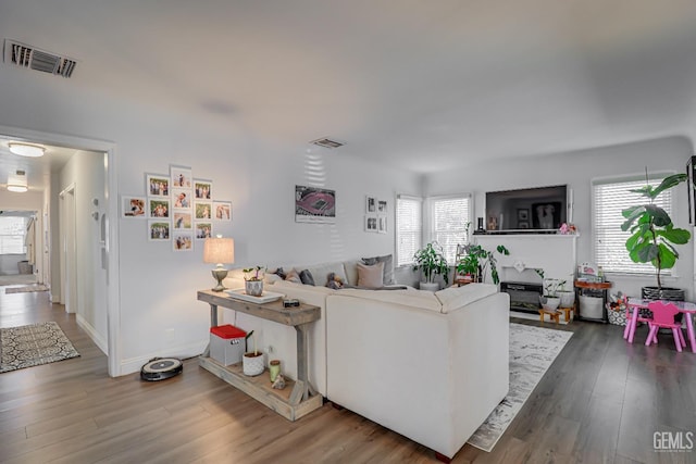 living area with baseboards, visible vents, and wood finished floors