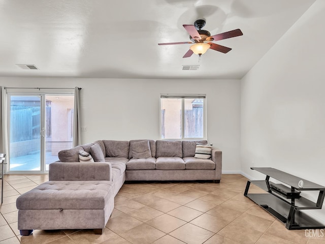 living area featuring baseboards, visible vents, light tile patterned floors, and a ceiling fan