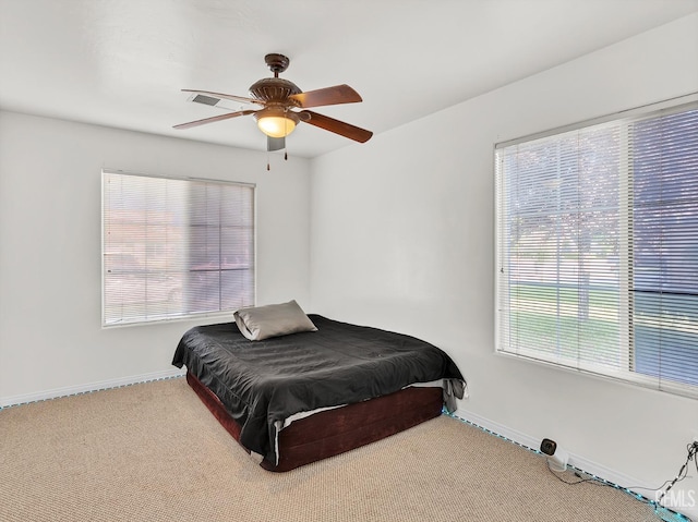 carpeted bedroom featuring ceiling fan, baseboards, and multiple windows