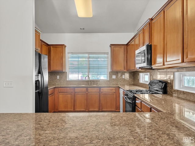 kitchen with black appliances, brown cabinets, decorative backsplash, and a sink