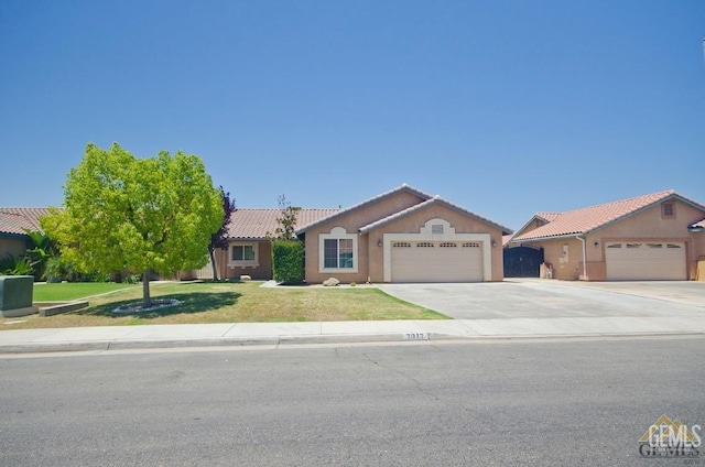 ranch-style home with a front yard, a tile roof, concrete driveway, and an attached garage