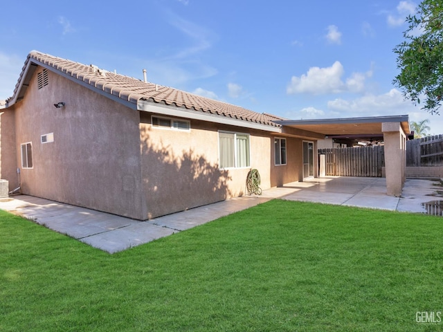 back of property with fence, a patio, a tile roof, stucco siding, and a yard
