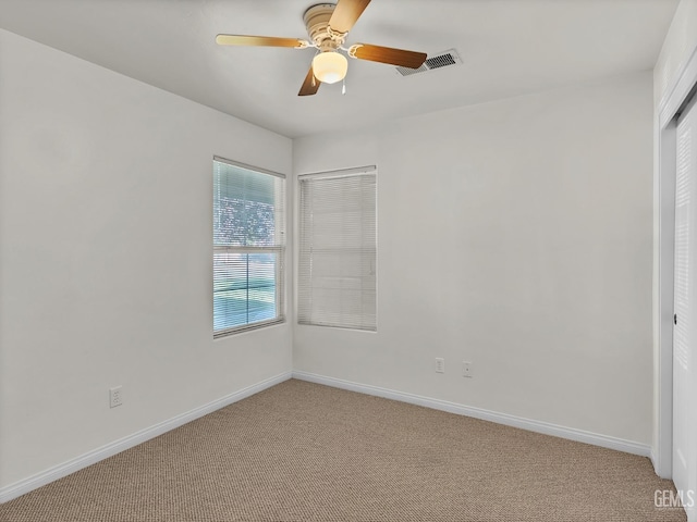 unfurnished bedroom with baseboards, visible vents, a ceiling fan, and light carpet