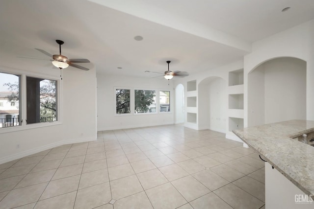 5507 Via Venezia, Bakersfield, CA 93306 - unfurnished living room with a ceiling fan, light tile patterned flooring, arched walkways, and baseboards