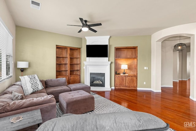9310 Via Catania, Bakersfield, CA 93312 - living room featuring wood finished floors, arched walkways, a glass covered fireplace, visible vents, and a ceiling fan