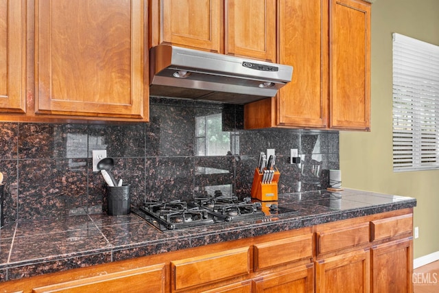 9310 Via Catania, Bakersfield, CA 93312 - kitchen featuring decorative backsplash, tile counters, under cabinet range hood, black gas cooktop, and brown cabinetry