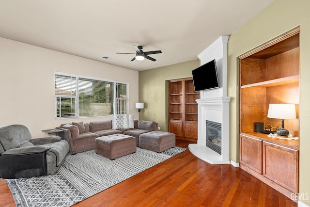 9310 Via Catania, Bakersfield, CA 93312 - living room with dark wood finished floors, ceiling fan, visible vents, and a glass covered fireplace