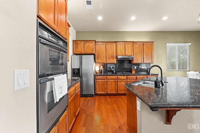 9310 Via Catania, Bakersfield, CA 93312 - kitchen featuring brown cabinets, a sink, under cabinet range hood, wood finished floors, and stainless steel fridge with ice dispenser
