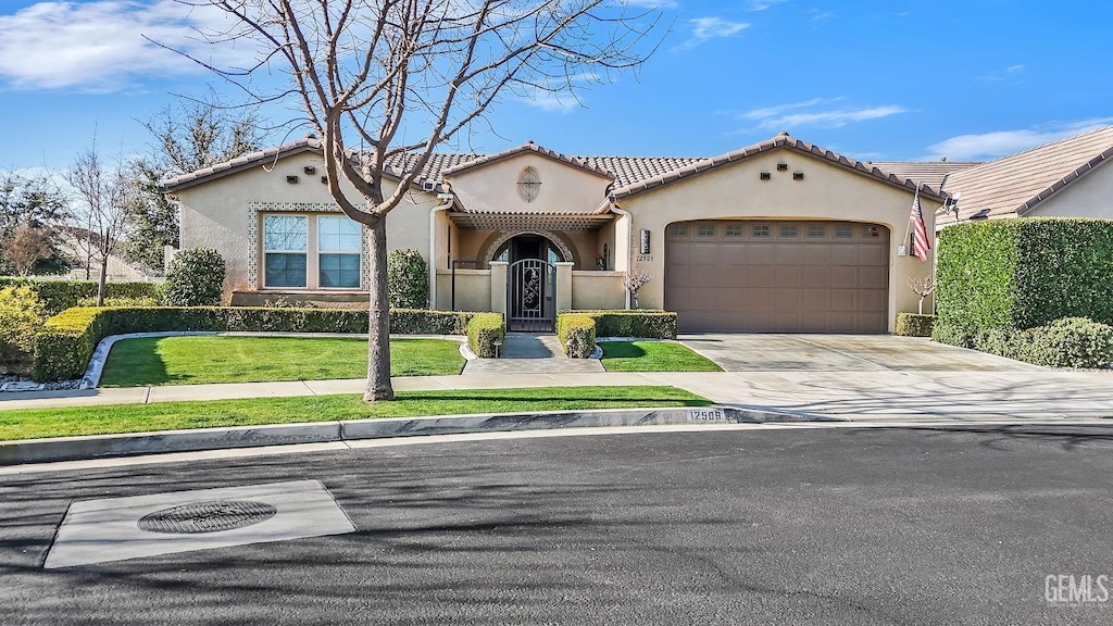 mediterranean / spanish home with a garage and a front lawn