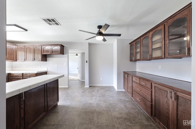 2800 S Real Rd, Bakersfield, CA 93309 - kitchen featuring glass insert cabinets, a ceiling fan, tile counters, and baseboards