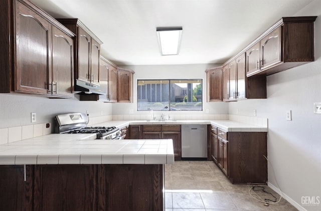 2800 S Real Rd, Bakersfield, CA 93309 - kitchen with stainless steel appliances, under cabinet range hood, a peninsula, and dark brown cabinetry