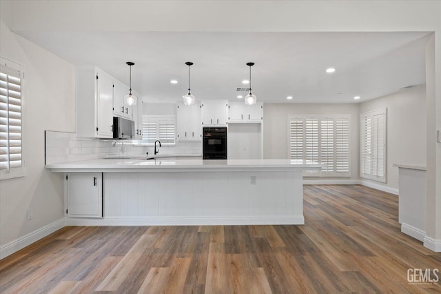5100 Ruth Ct, Bakersfield, CA 93308 - kitchen featuring a peninsula, light countertops, white cabinets, wood finished floors, and recessed lighting