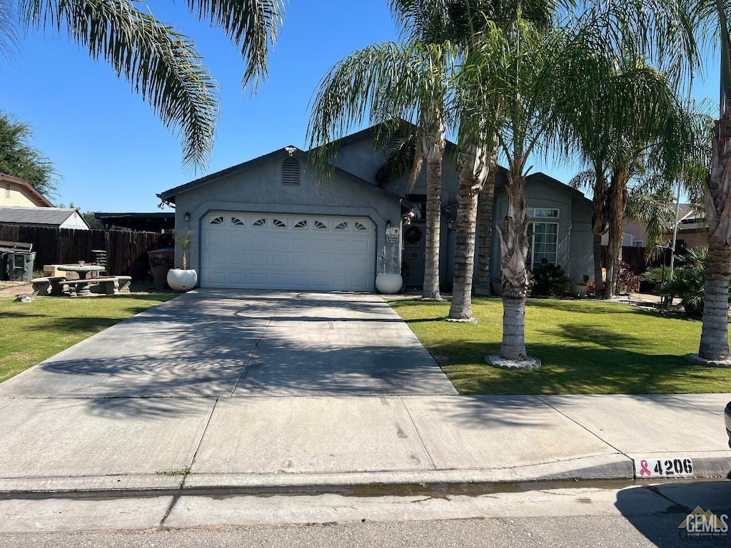 view of front facade featuring stucco siding, driveway, fence, an attached garage, and a front yard