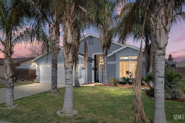 view of front of property with fence, a yard, stucco siding, concrete driveway, and a garage