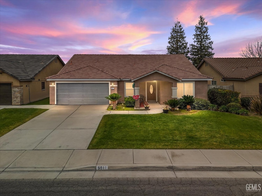 single story home with a tile roof, a yard, stucco siding, concrete driveway, and an attached garage