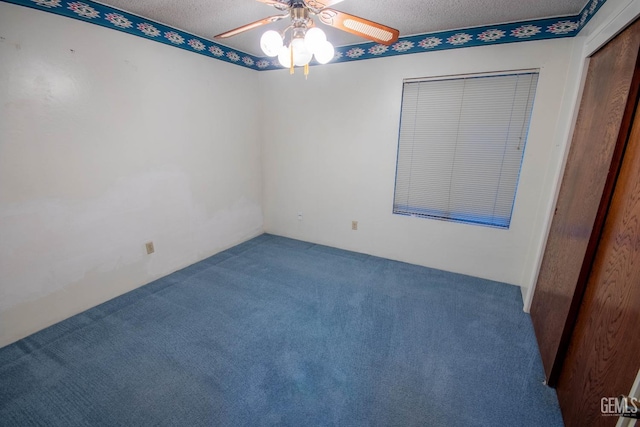 carpeted empty room with a ceiling fan and a textured ceiling