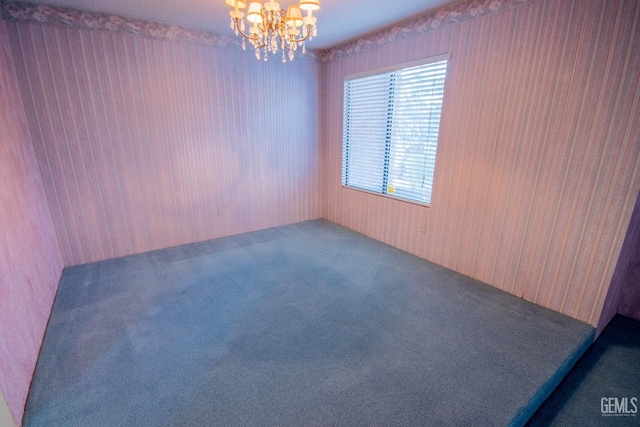 empty room featuring carpet floors and a notable chandelier