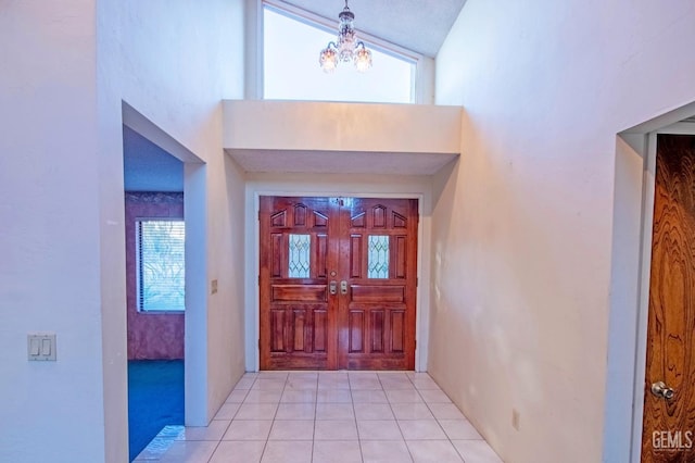 foyer entrance with a high ceiling, a chandelier, and light tile patterned flooring