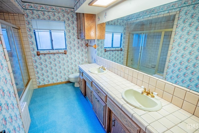 bathroom featuring baseboards, a sink, toilet, and wallpapered walls