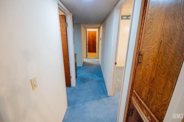 hall with light carpet and a textured ceiling