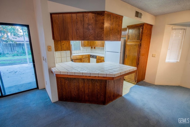 kitchen with tile countertops, a peninsula, white appliances, and brown cabinets