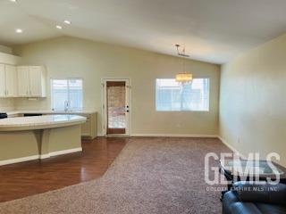 kitchen with white cabinets, plenty of natural light, baseboards, and lofted ceiling