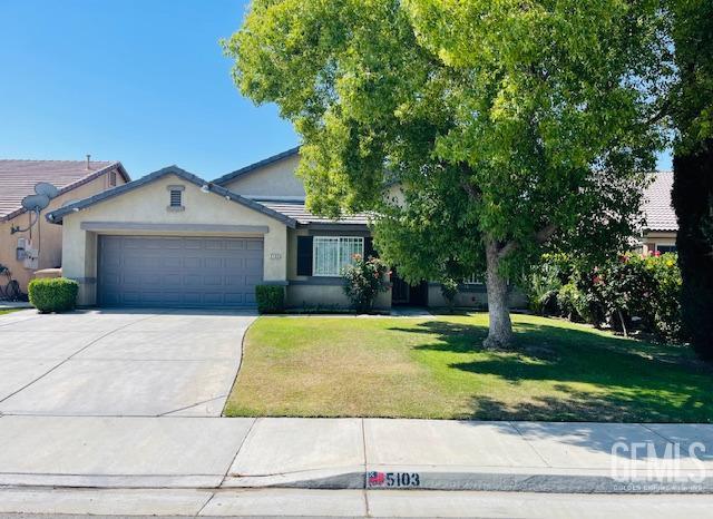 view of front of property featuring concrete driveway, stucco siding, a front lawn, and an attached garage