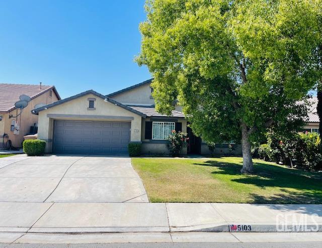 view of front of property with concrete driveway, a front yard, stucco siding, and a garage