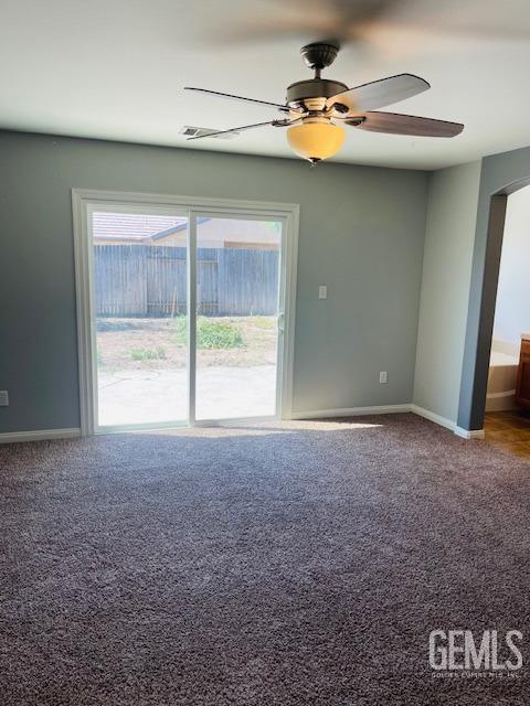 empty room featuring carpet, arched walkways, baseboards, and a ceiling fan