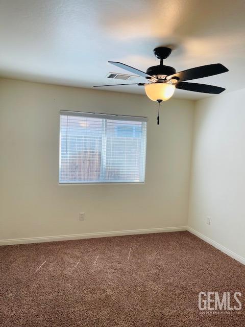 carpeted spare room with visible vents, baseboards, and a ceiling fan