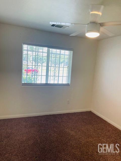 carpeted empty room featuring baseboards, a ceiling fan, plenty of natural light, and visible vents