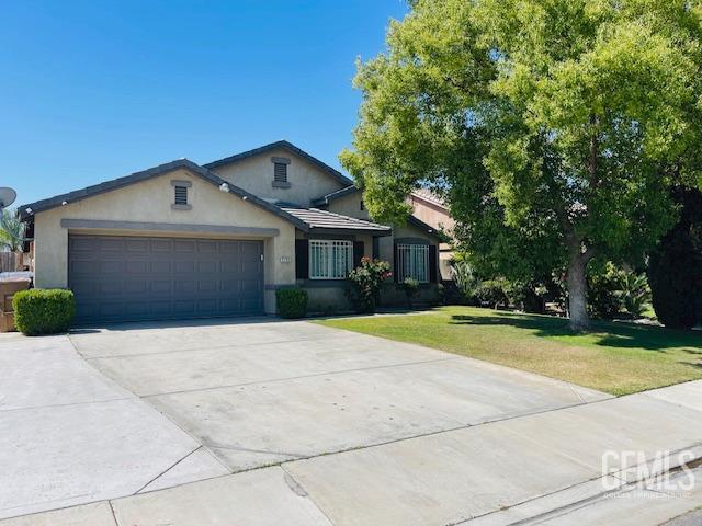view of front of home with an attached garage, concrete driveway, stucco siding, and a front yard