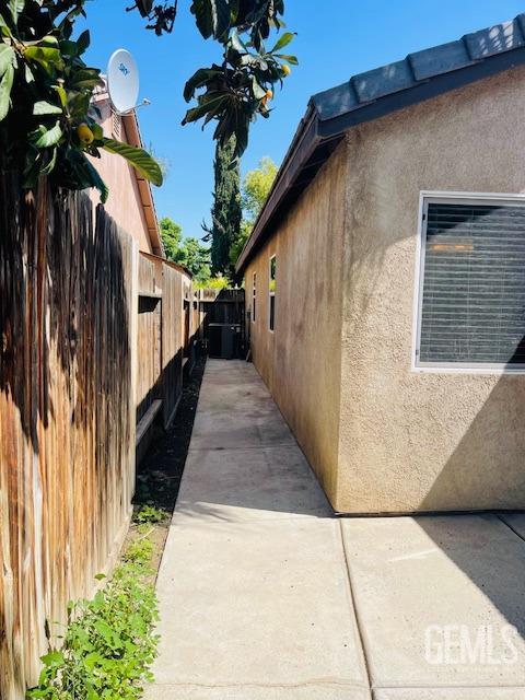 view of property exterior with stucco siding and fence