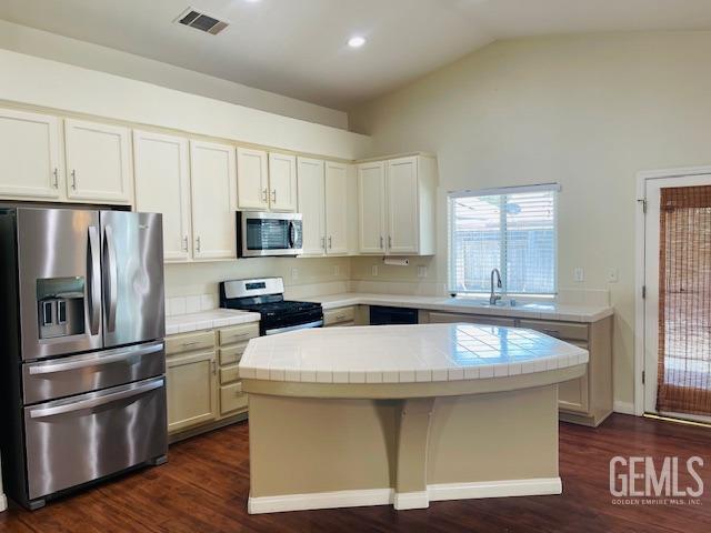 kitchen featuring a kitchen island, tile countertops, stainless steel appliances, and visible vents