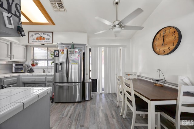 6305 Wolfe Creek Dr, Bakersfield, CA 93306 - kitchen with stainless steel refrigerator with ice dispenser, tile counters, ceiling fan, light wood-style flooring, and lofted ceiling