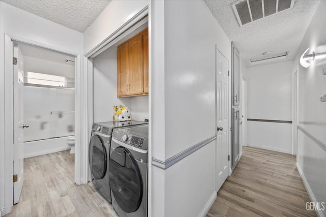 6305 Wolfe Creek Dr, Bakersfield, CA 93306 - washroom featuring a textured ceiling, cabinet space, light wood-style floors, and washing machine and dryer