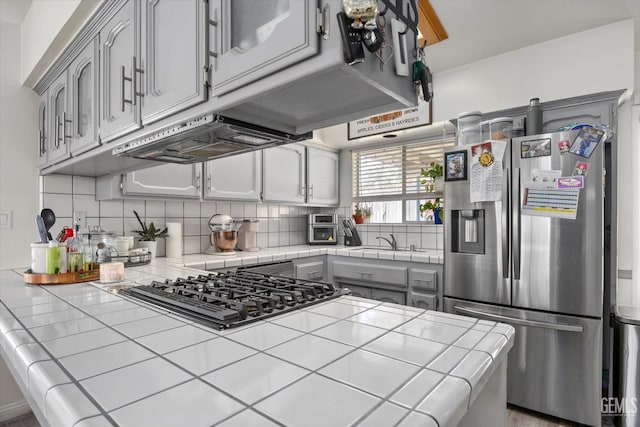 6305 Wolfe Creek Dr, Bakersfield, CA 93306 - kitchen featuring stainless steel fridge with ice dispenser, tile counters, black gas stovetop, tasteful backsplash, and gray cabinetry
