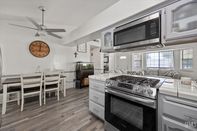 6305 Wolfe Creek Dr, Bakersfield, CA 93306 - kitchen featuring stainless steel appliances, tile countertops, light wood-type flooring, a ceiling fan, and vaulted ceiling