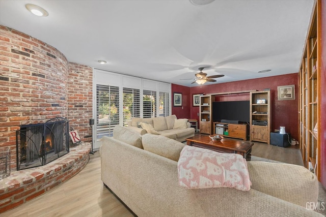 living area featuring ceiling fan, a fireplace, and wood finished floors