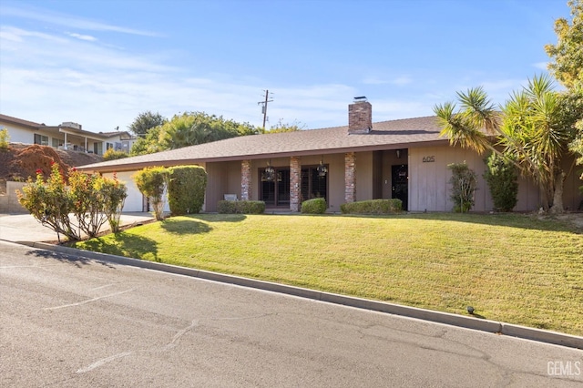 ranch-style home with a shingled roof, concrete driveway, a chimney, an attached garage, and a front lawn