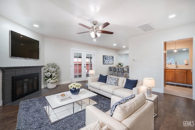 living room with recessed lighting, dark wood finished floors, visible vents, french doors, and a glass covered fireplace