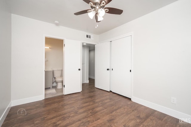 unfurnished bedroom featuring baseboards, visible vents, ensuite bath, dark wood-type flooring, and a closet