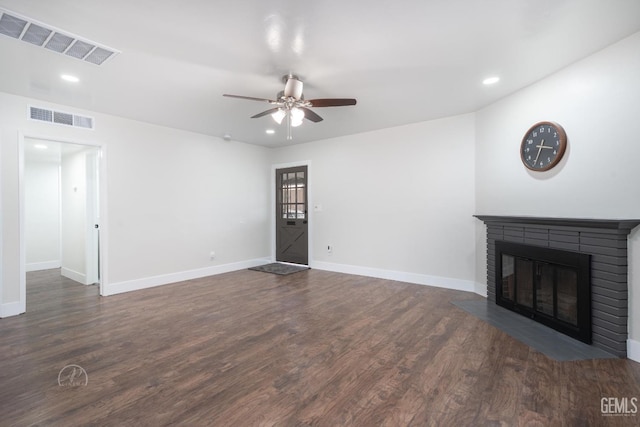 unfurnished living room featuring dark wood-style flooring, a brick fireplace, and visible vents