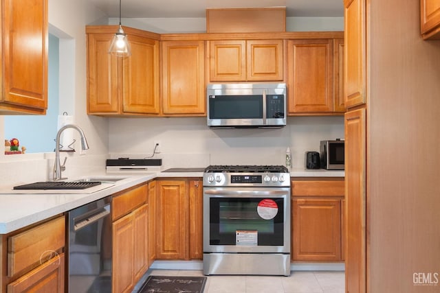 kitchen featuring stainless steel appliances, a sink, hanging light fixtures, light countertops, and brown cabinets