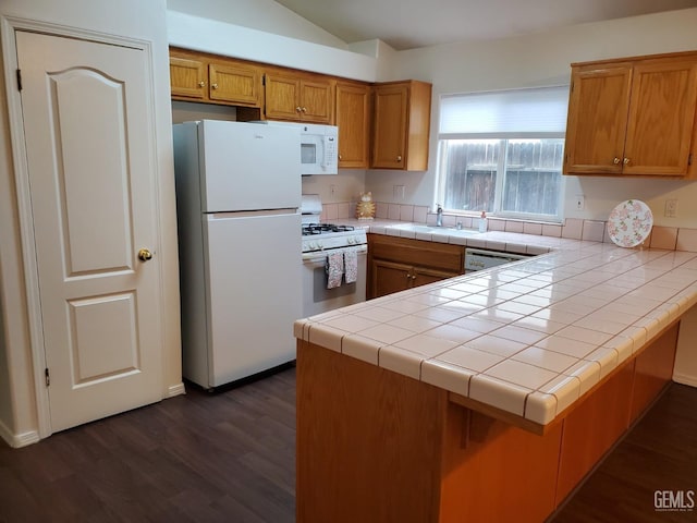 kitchen with dark wood-type flooring, sink, tile countertops, kitchen peninsula, and white appliances