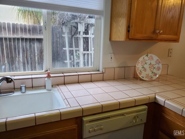 kitchen with white dishwasher, tile countertops, and plenty of natural light