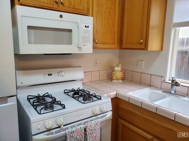 kitchen featuring white appliances, tile countertops, and sink